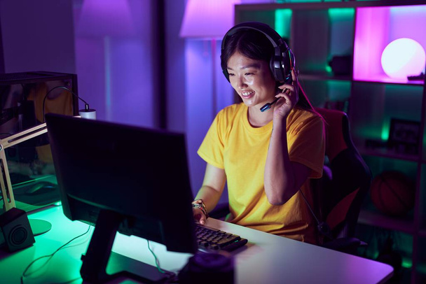 Chinese vrouw streamer glimlachen zelfverzekerd met behulp van computer bij gaming room - Foto, afbeelding