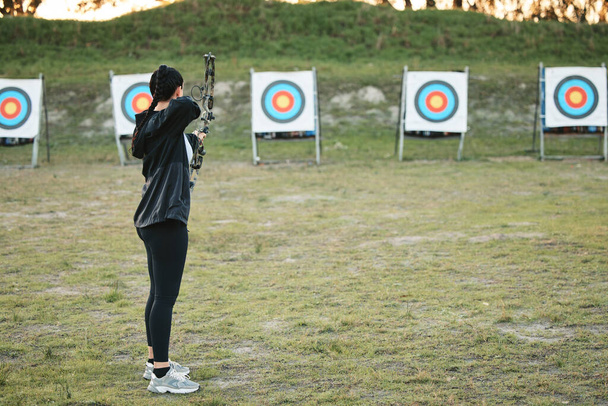 Sports, archery target and bow and arrow training for archer competition, athlete challenge or girl field practice. Shooting, objective and competitive woman focus on precision, aim or outdoor mockup. - Photo, Image