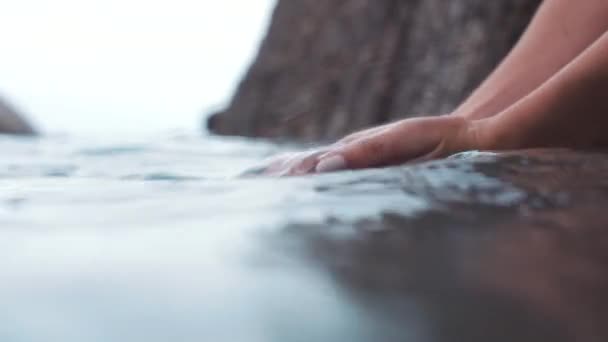 Hand, water en natuur met een vrouw aan het strand met haar handen in de oceaan of zee. Fris, wellness en natuurlijke hydratatie met een vrouwelijke outdoor alleen en de lucht op de achtergrond van onderen. - Video