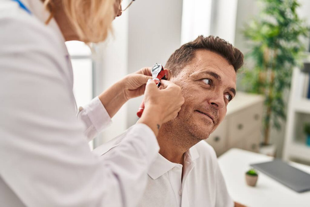 Medico e paziente di mezza età che esamina l'orecchio con consulto medico presso la clinica - Foto, immagini