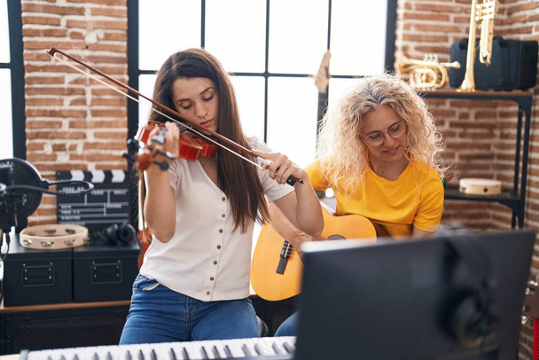 Dos mujeres músicos tocando violín y guitarra clásica en el estudio de música - Foto, imagen