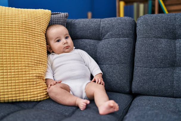 Sevimli bebek evdeki kanepede rahat rahat oturuyor. - Fotoğraf, Görsel