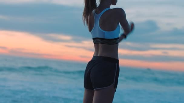 Γυμνασμένη, δραστήρια και αθλητική γυναίκα που τεντώνεται, ετοιμάζεται και προετοιμάζεται για προπόνηση, άσκηση και προπόνηση σε παραλία το ηλιοβασίλεμα. Σοβαρή, με κίνητρο και αυτοπεποίθηση αθλητής σε ένα πρωινό τρέξιμο δίπλα στη θάλασσα. - Πλάνα, βίντεο