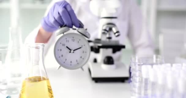 Reloj con cristalería química para investigación médica en laboratorio en manos de científicos. Tiempo experimentos de investigación química médica y control - Metraje, vídeo