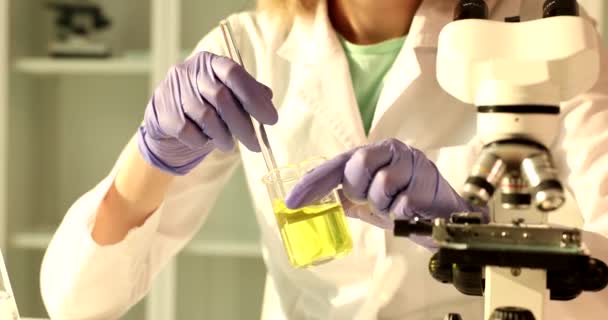 Chemist scientist holds and stirs in hands flask with yellow liquid in chemical laboratory. Quality control of petrochemical products - Footage, Video