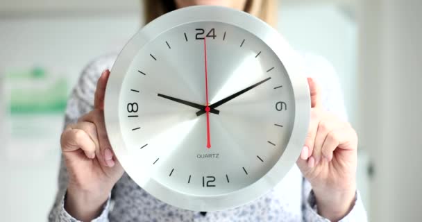 Businesswoman in office holding stylish wall clock closeup. Overtime deadline and working time scheduling - Filmagem, Vídeo