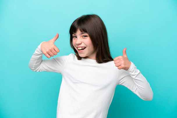 Little caucasian girl isolated on blue background giving a thumbs up gesture - Photo, Image