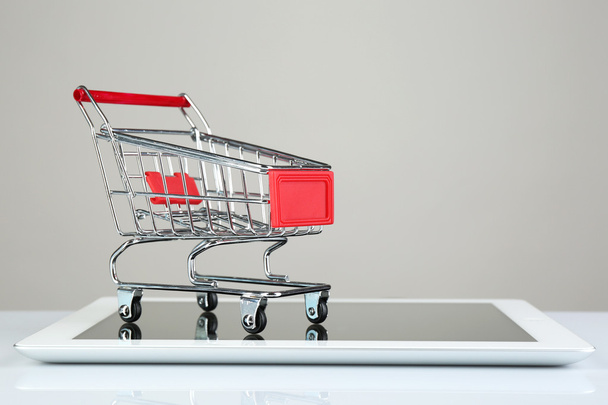 Tablet with small shopping cart isolated on white background - Φωτογραφία, εικόνα