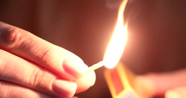 Woman strikes match and lights it on black background. Turning off the lights and using matches - Video, Çekim
