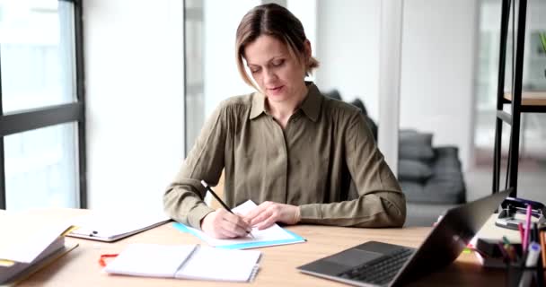Ofisteki iş yerindeki not defterine düşünceli bir kadın notlar yazıyor. Planlama günü ve yaratıcı fikirleri kaydetmek - Video, Çekim
