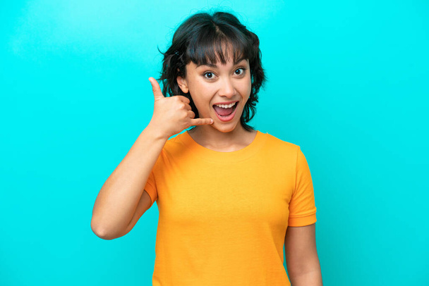 Young Argentinian woman isolated on blue background making phone gesture. Call me back sign - 写真・画像