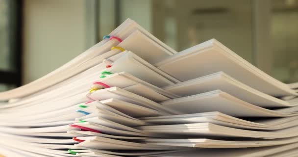 Pino ylikuormitettua asiakirjapaperia, jossa värikäs paperiliitin pöydällä. Byrokraattinen liiketoimintakonsepti ja liiketoimintaasiakirjojen käsittely - Materiaali, video