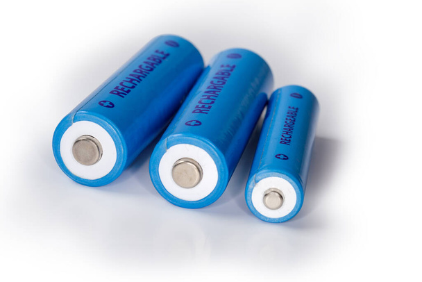 Blaue wiederaufladbare Nickel-Metallhydrid-Batterien der Größen AA und AAA auf weißer Oberfläche, Nahaufnahme im selektiven Fokus - Foto, Bild