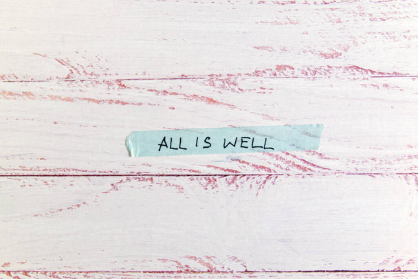 motivational message 'all is well' handwritten on colorful washi tape against white wooden background - Foto, immagini