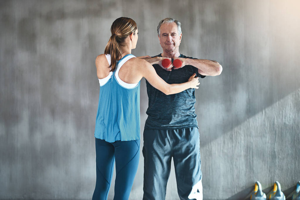 La fisioterapia ayuda a mejorar su función muscular y articular. un hombre mayor que usa pesas con la ayuda de un fisioterapeuta - Foto, Imagen