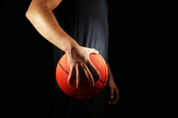 Jogador de basquete segurando bola, no fundo escuro
 - Foto, Imagem