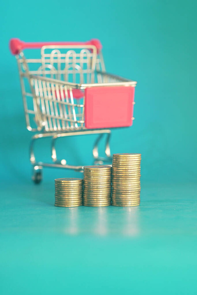 gold coins in shopping cart on blue background - Photo, Image