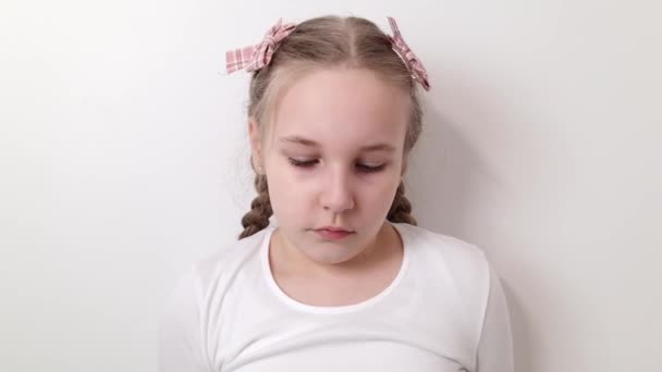 Sad stressed little girl expressing negative emotions, sorrow, bad mood. Female kid isolated on white background - Materiaali, video