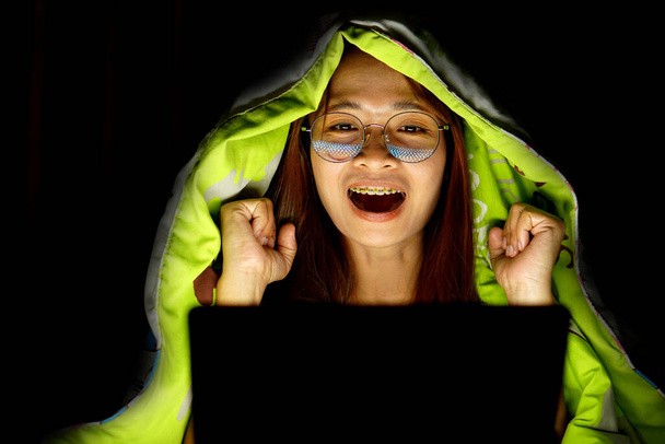 Asian woman wearing glasses To view the computer in low light watch movies online - Foto, Imagem