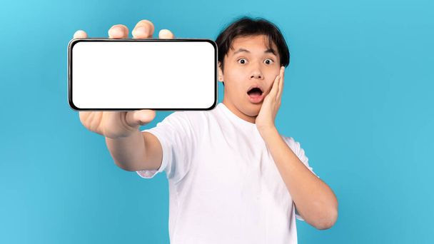 Шутливый японский мальчик-подросток, снимающий на фоне синего студийного фона. Omg, Great Mobile Offer And Application Ad. Мбаппе, Маккаби - Фото, изображение