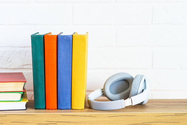 Concept de livres audio. Casques sans fil et livres de couleurs à la table en bois fond blanc. - Photo, image