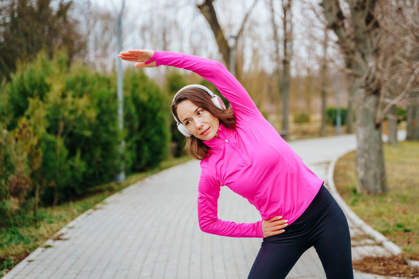 Egy sportos nő edz a szabadban, élvezi az egészséges életmódot és aktív marad fejhallgatóval a fején. - Fotó, kép