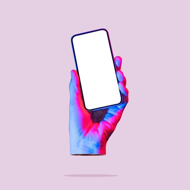 The hand holds a smartphone with a white screen. Art collage. Mockup. - Photo, image