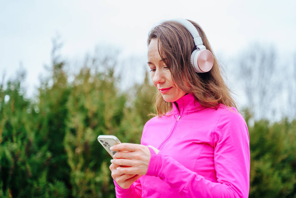 pretty woman surrounded by nature and free from the stresses of everyday life With her headphones and smartphone, shes able to stay connected - Zdjęcie, obraz