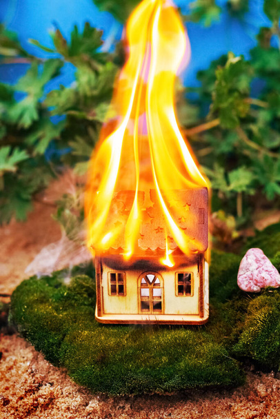 A toy wooden house is burning in nature. Fire concept. Fire safety - Foto, Imagem