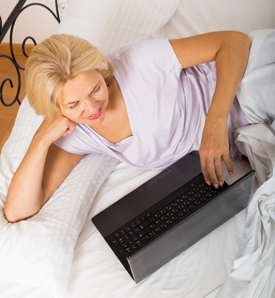 Mature woman with laptop in bed - Fotografie, Obrázek