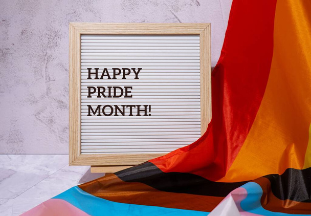 HAPPY PRIDE MONTH inscription positive quote phrase text frame on Rainbow LGBTQIA flag made from silk material. Symbol of LGBTQ pride month. Equal rights. Peace and freedom. Support LGBTQIA community - Foto, Imagen