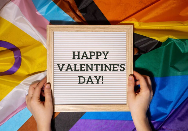 Happy VALENTINESシルク素材で作られたレインボーLGBTQIAフラグのDAYテキストフレーム。LGBTQプライド月間のシンボル。平等な権利。平和と自由。LGBTQIAコミュニティを支援する。多様性平等 - 写真・画像