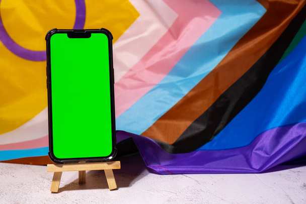 Mobile phone with chroma key on Rainbow LGBTQIA flag made from silk material background. Happy pride month. Symbol of LGBTQ pride month. Equal rights. Peace and freedom. Support LGBTQIA community - Foto, Imagen