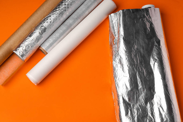 Rolls of aluminium foil, baking paper and food film on orange background - Photo, Image
