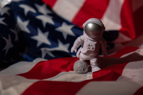Plastic toy figure astronaut on American flag background Copy space. 50th Anniversary of USA Landing on The Moon Concept of out of earth travel, private spaceman commercial flights. Space missions and - 写真・画像