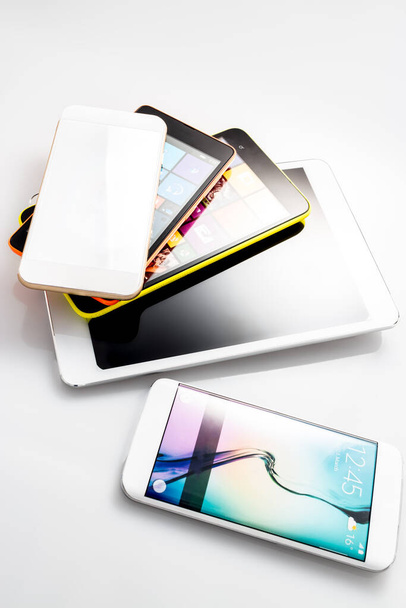 Group of smartphones, cell phones, digital tablets and mobile technology devices, grouped together but isolated on a white or shaded background. - Foto, Imagen