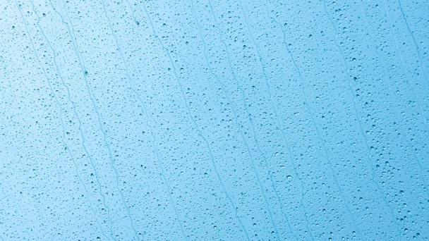 Σταγόνες βροχής στο γυαλί να εκτελέσει το γαλάζιο του ουρανού - Πλάνα, βίντεο