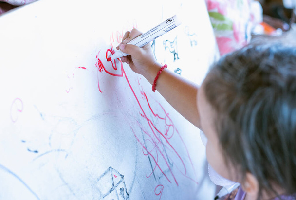 A cute little girl is drawing a messy picture. - Фото, зображення