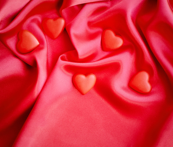 Red hearts on satin fabric background - 写真・画像