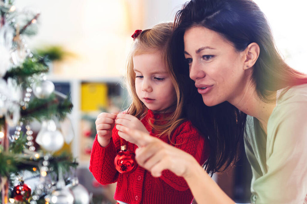 beautiful mother and daughter decorating christmas tree - Photo, Image