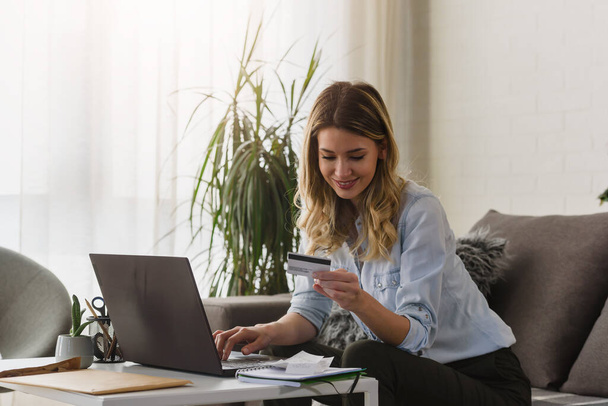 krásná mladá žena s notebookem a kreditní kartou ve své kanceláři dělat online objednávky - Fotografie, Obrázek