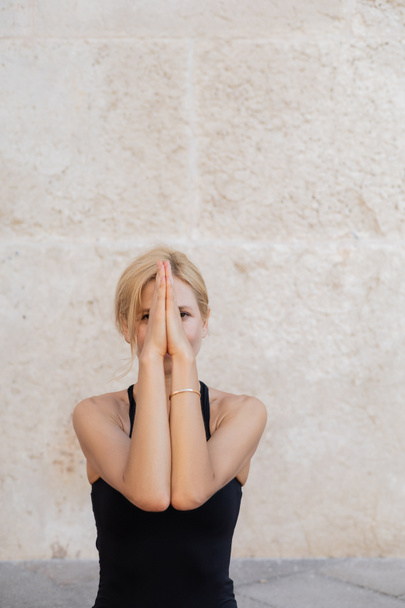 Blonde woman covering face with hands while meditating outdoors in Venice  - Photo, Image