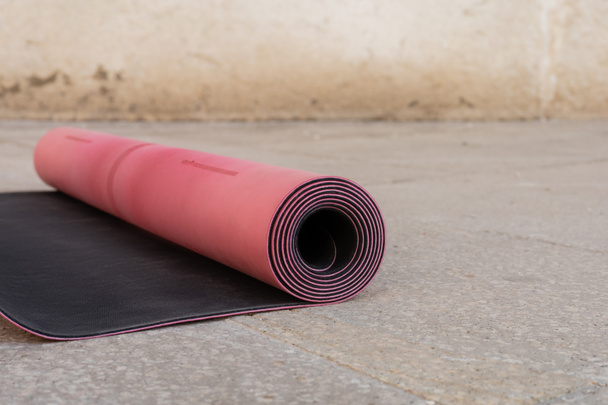 vista de cerca de la alfombra de fitness rosa y negro en la acera al aire libre, espacio para copiar, estilo de vida urbano  - Foto, imagen