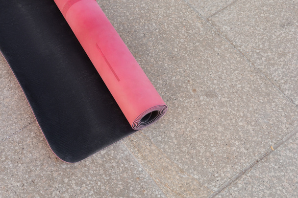 Top view of pink fitness mat on asphalt sidewalk outdoors, copy space, urban lifestyle  - Photo, Image