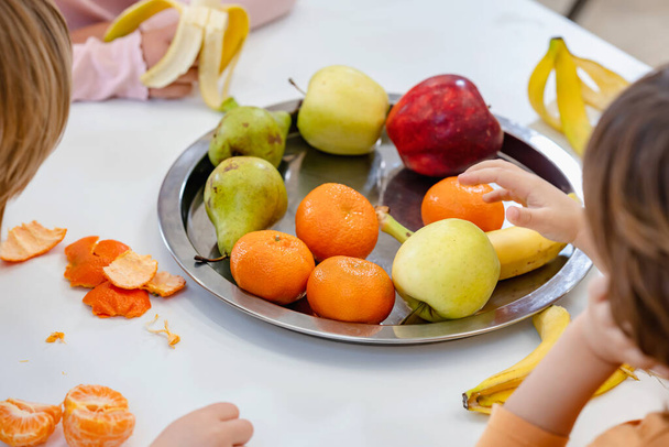 children eating fruits at lunch break in kindergarten - 写真・画像