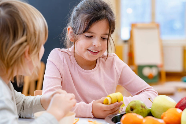 chlapec a dívka jíst ovoce na přestávce na oběd ve školce - Fotografie, Obrázek