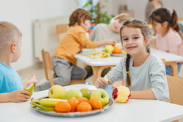 παιδιά που τρώνε φρούτα στο διάλειμμα για φαγητό στο νηπιαγωγείο - Φωτογραφία, εικόνα