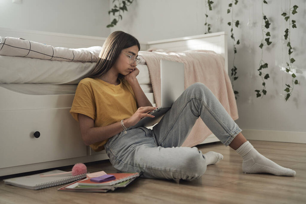 Caucasian teenager sitting on floor and learning from books and laptop - Photo, Image