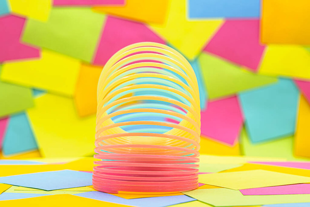 Toy plastic rainbow on a multicolored paper sticky notes on background, color spiral for play - Foto, afbeelding