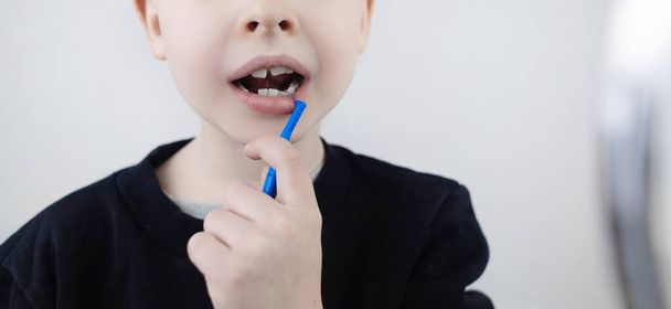 Zahnheilkunde und Kieferorthopädie. Zahnzwischenraumbürste. Ein blonder Junge zeigt eine Bürste zur Reinigung des Zahnzwischenraums. Zähneputzen und tägliche Mundpflege.  - Foto, Bild